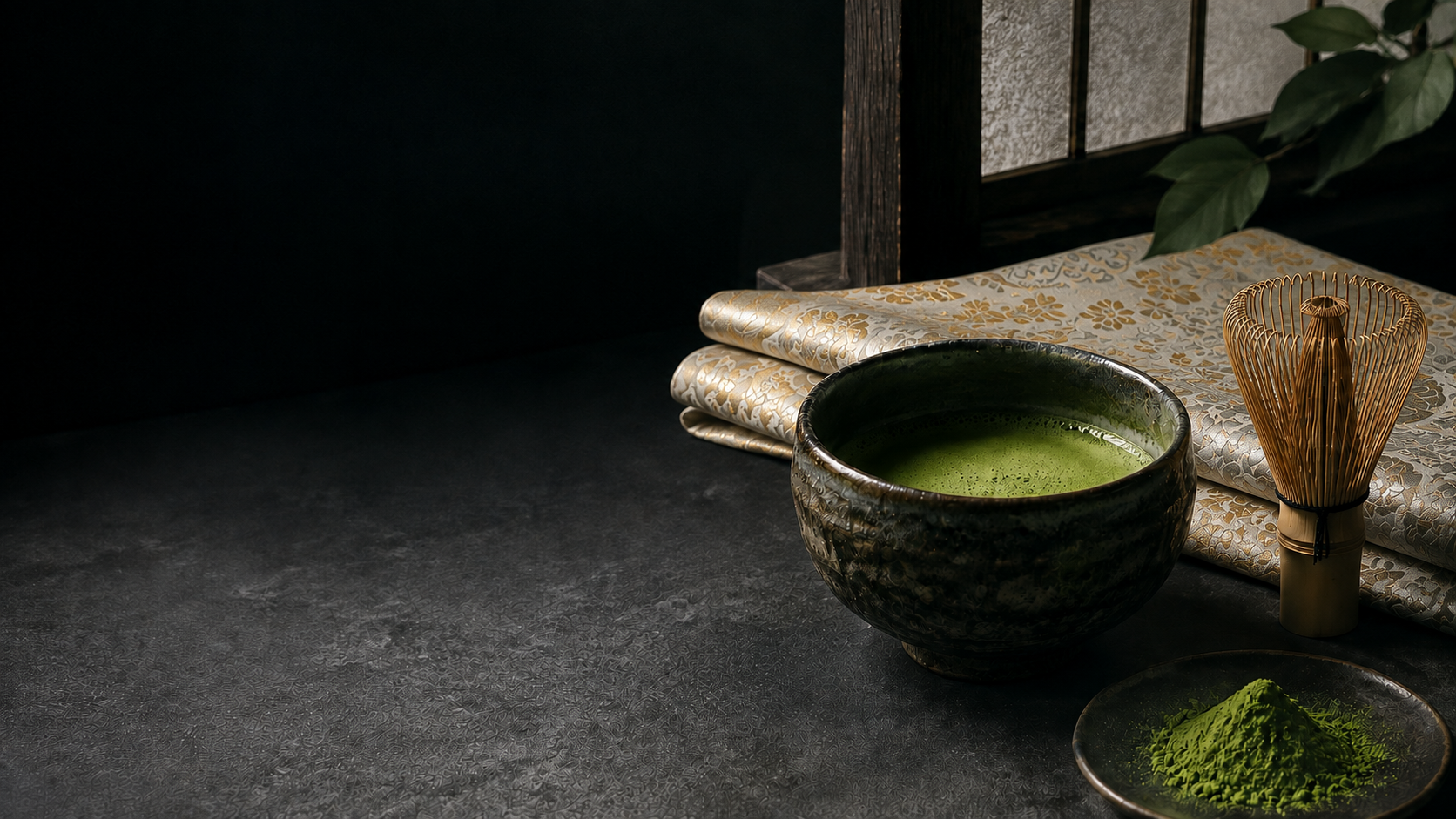 Matcha and a bamboo whisk with a bright ivory obi woven with gold and silver threads in the background